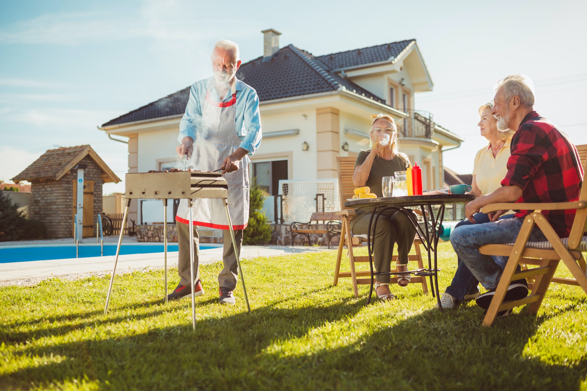 Senior neighbors having backyard barbecue party